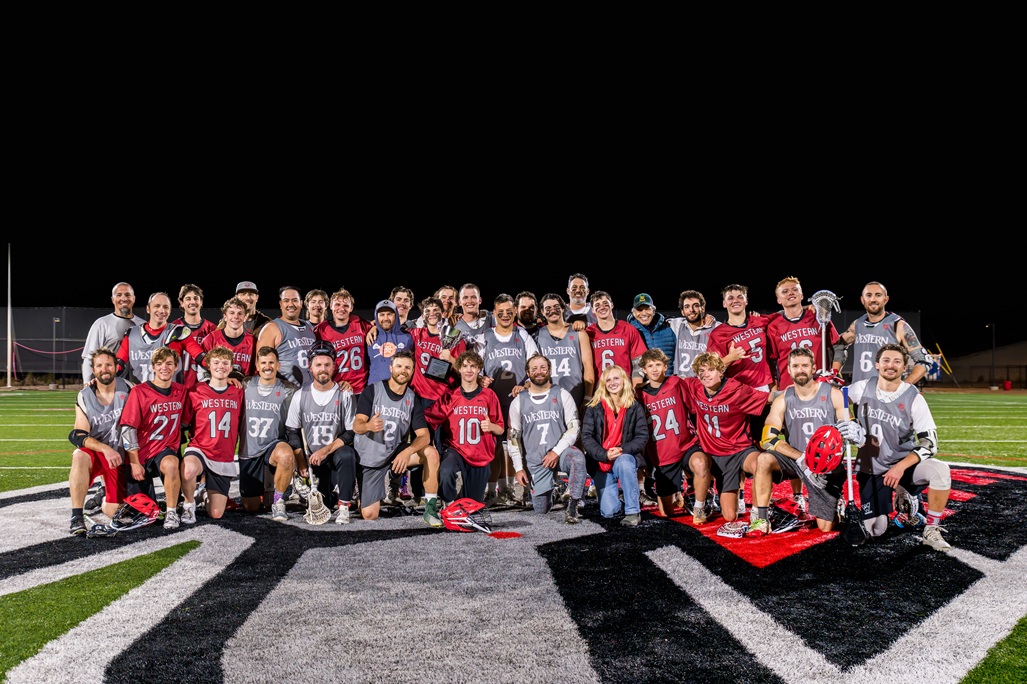 Lacrosse team group photo on football field.
