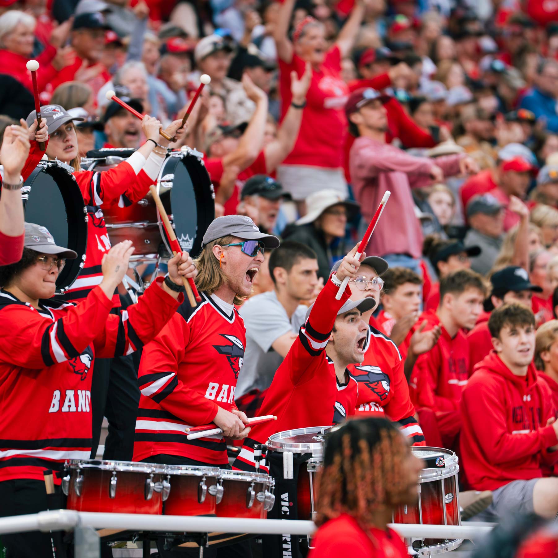 Students on the drumline cheer with excitement from their spot in the stands during a football game in the Mountaineer Bowl.