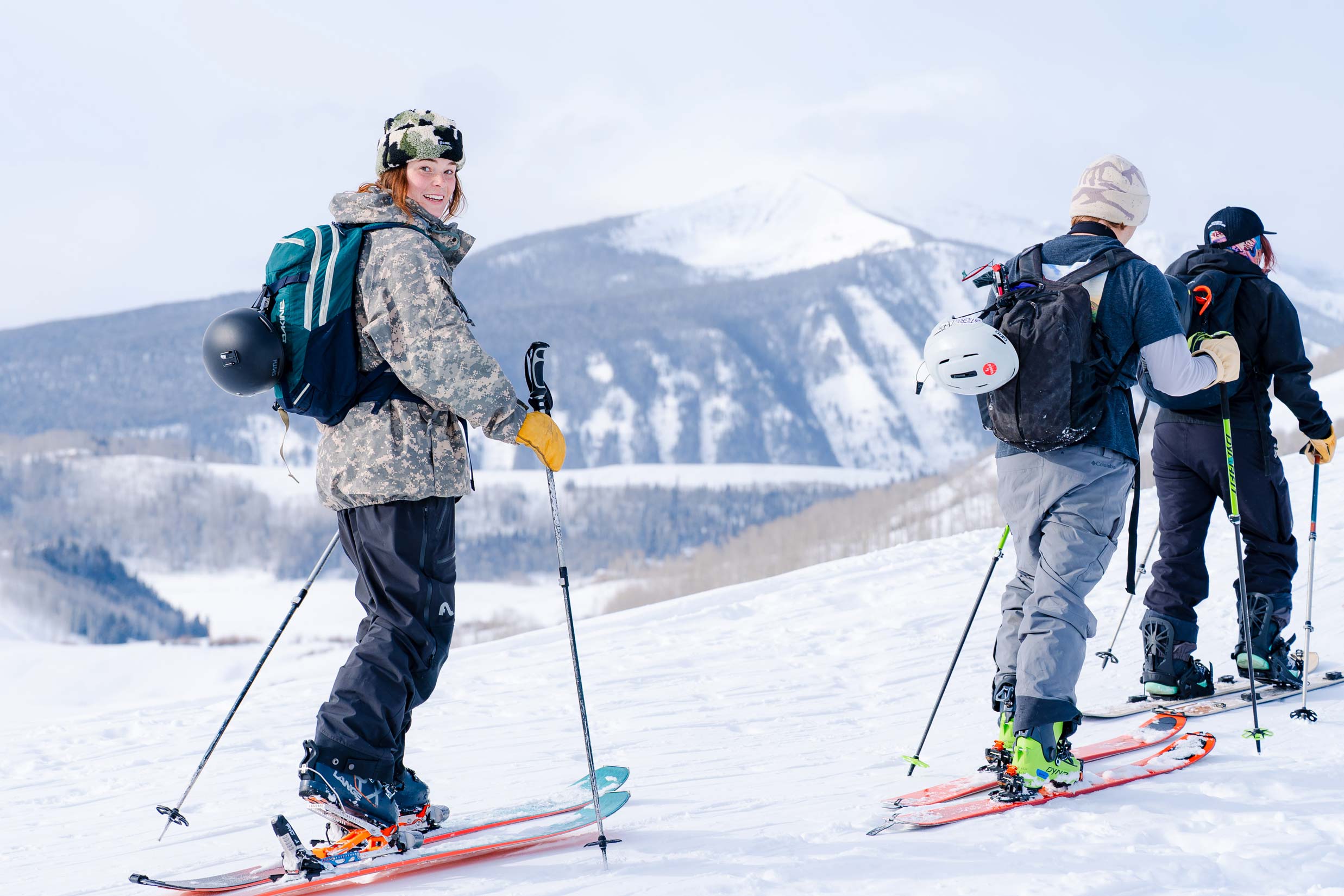 Clara Lantz smiles as she skins up Snodgrass Mountain. Frosty mountains are seen behind her.