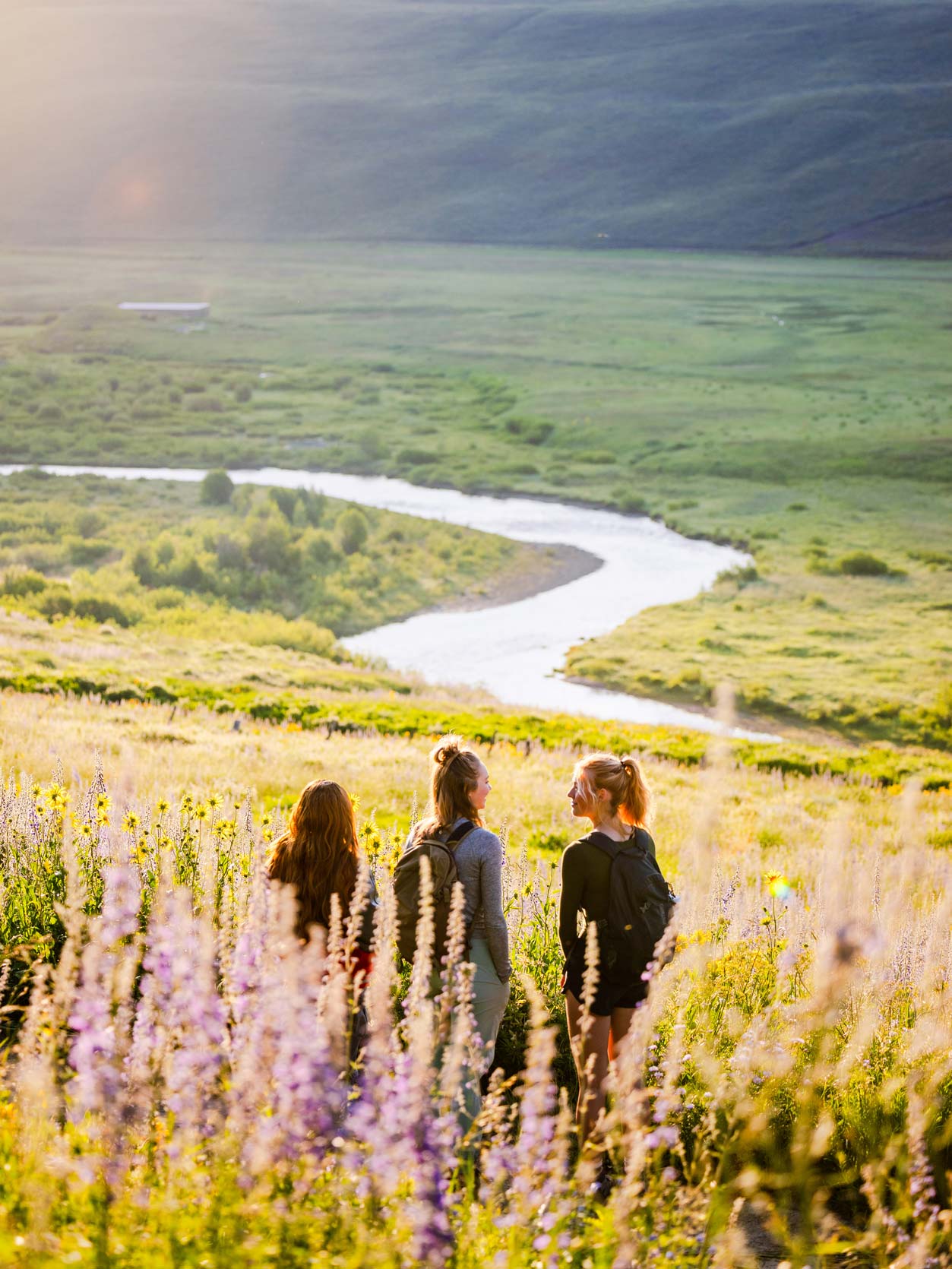 Three students watch the sunrise on the East River Trail.